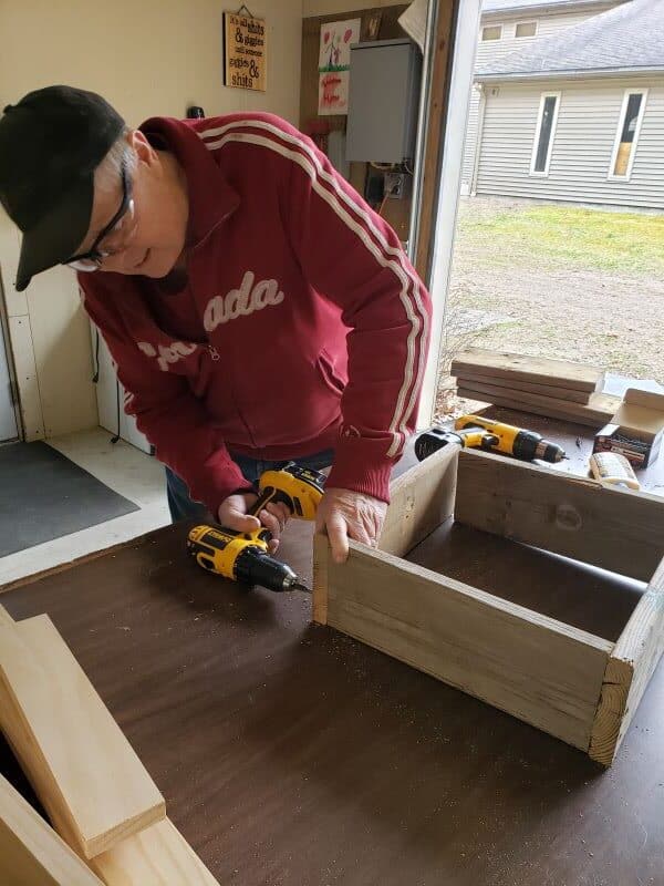 hombre montando una caja de juego de lanzamiento de arandelas con un taladro manual